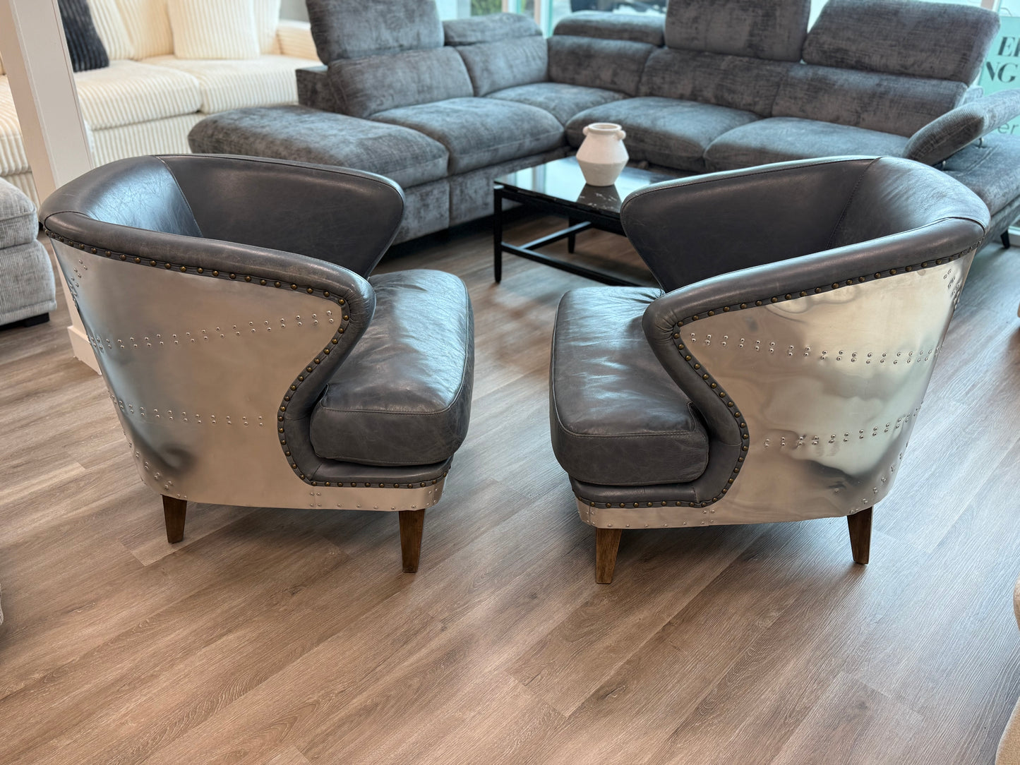 Two gray armchairs in a living room setting with a sectional sofa and coffee table.