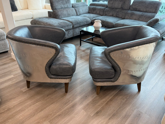 Two gray armchairs in a living room setting with a sectional sofa and coffee table.