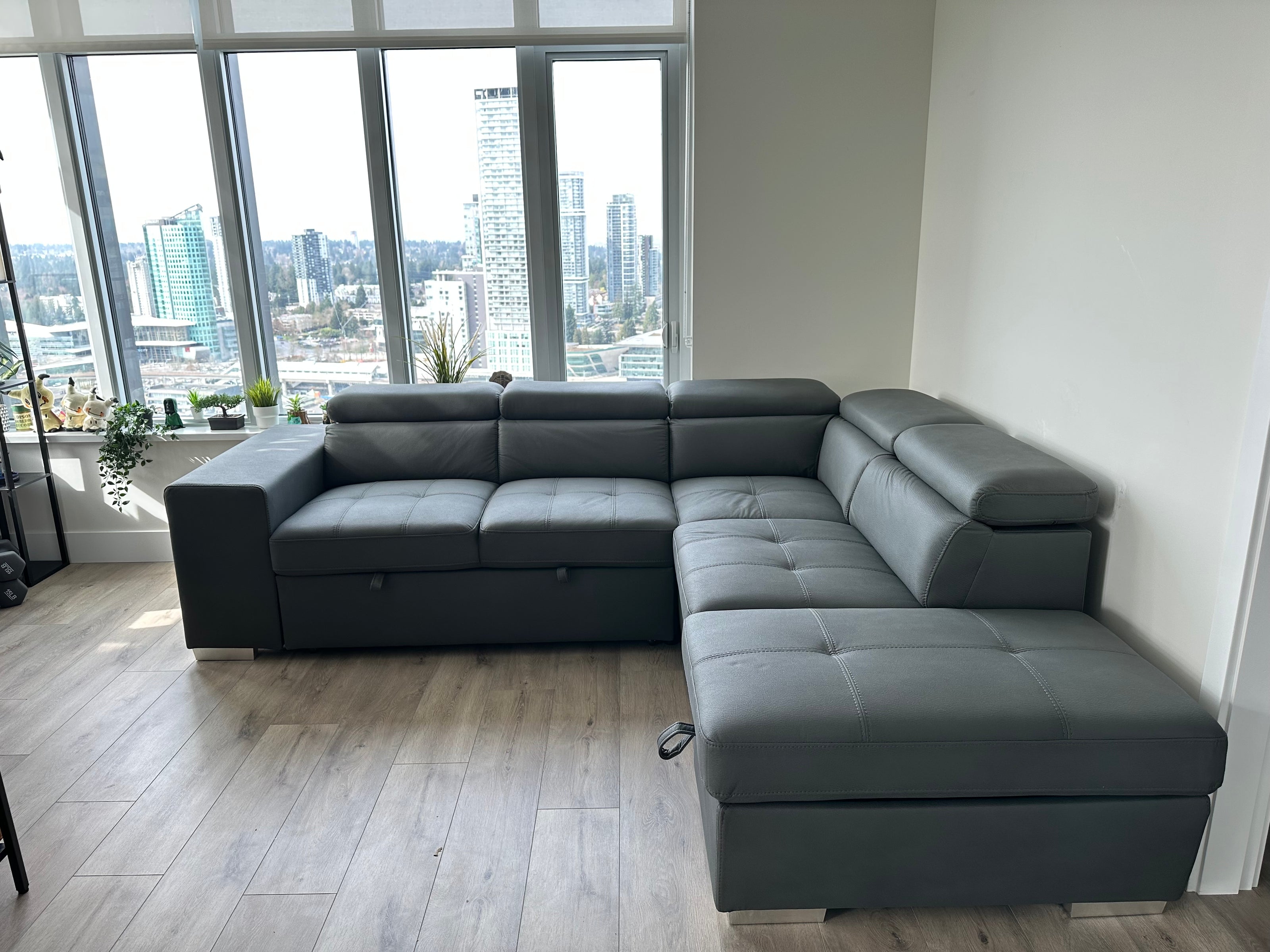 Gray sectional sofa in a room with large windows showing a cityscape.