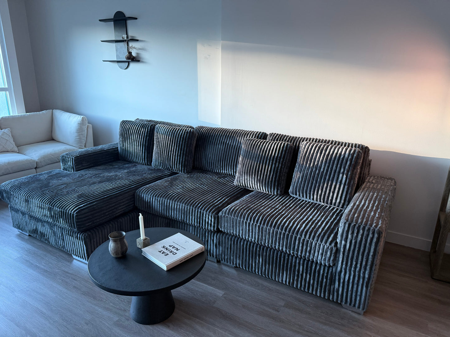 Gray Soft corduroy sectional sofa in a living room with a small round table and decor items.