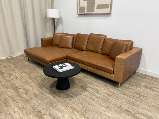 Camel leather sectional sofa in a living room setting with a black coffee table.